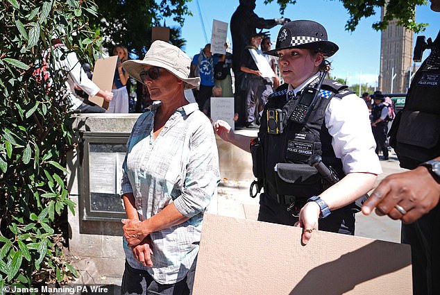 The protesters held signs reading: 'I oppose genocide. I support Palestine Action' whcih were taken off them by officers