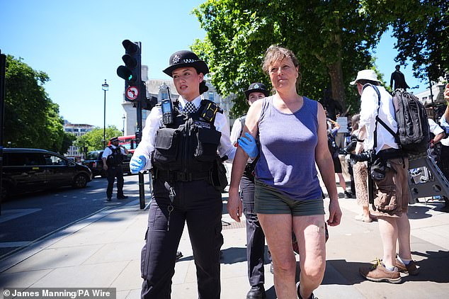 A protestor being led away by a Met Police officer after protesting outside Parliament today