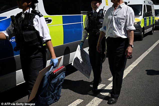Police carry demonstrators bags and signs after arresting them for supporting Palestine action