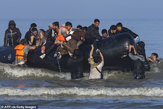 Migrants boarding a boat in an attempt to cross the English Channel last month. The number of small boats arrivals is surging, as migrants think Britain is powerless to stop them