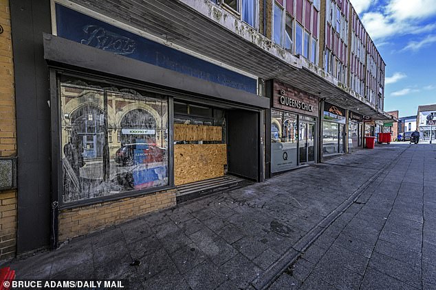 A Boots lays empty in a rundown building. Along the road also sits an empty letting agent, a courier shop, an insurance broker and a takeaway