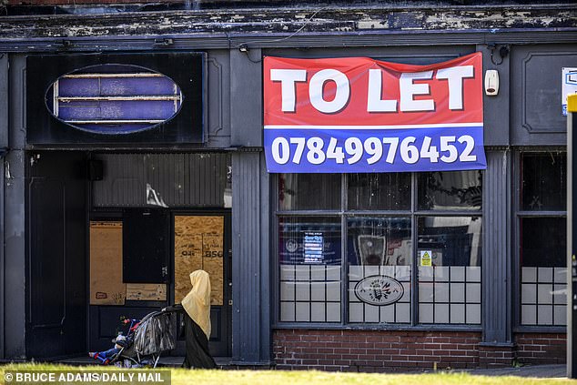A woman walking past yet another closed business with a large 'To Let' sign