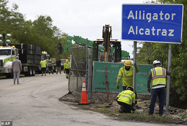 Workers install a sign reading 'Alligator Alcatraz' at the entrance to a new migrant detention facility. The first detainees arrived on July 3