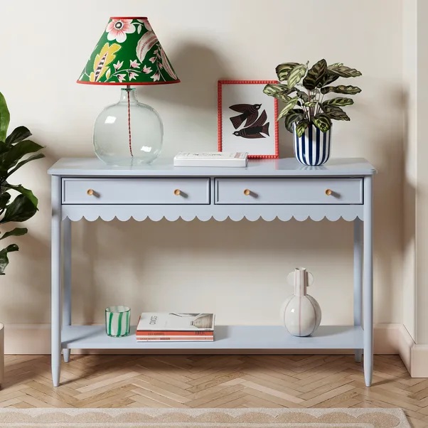 Pale blue console table with scalloped edge, two drawers, and a lower shelf.