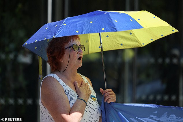 MANCHESTER: A woman uses a yellow and blue umbrella to cover herself from the scorching sun on July 12, 2025