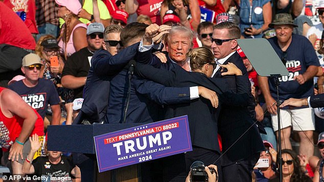 Trump lifts himself above his Secret Service protectors - a move Mitchell says reflects his refusal to be concealed, and his instinctive need to dominate the frame