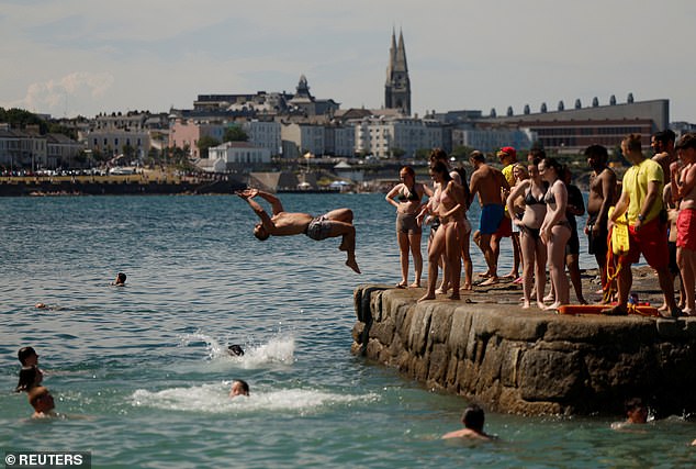Parts of the UK are set to experience rain showers on Monday, as fresh and cool temperatures come in from the west, the Met Office has said. Pictured: a man jumps off a pier in Sandycove, Ireland, on July 13, 2025