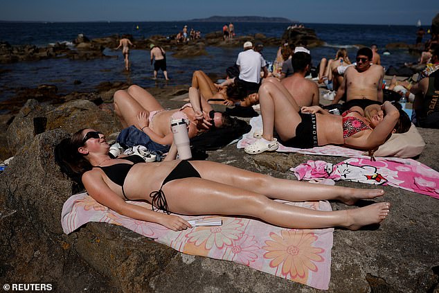 In Sandycove, Ireland, sunbathers relaxed on the rocks during the scorching heatwave that continued on July 13, 2025