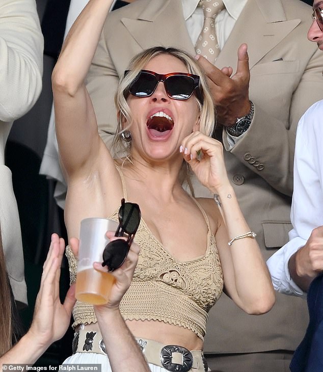 Sienna Miller, also wearing Ralph Lauren, looks jubilant as she dons sunglasses to watch the sport