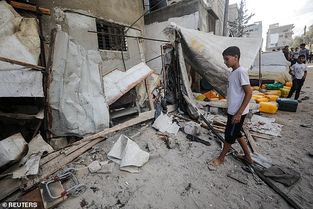 A Palestinian boy at the site of an Israeli strike that killed Palestinians, gathered to collect water from a distribution point