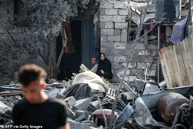 alestinians sit amid the rubble of a house in the aftermath of an overnight Israeli strike that hit Nuseirat in the central Gaza Strip