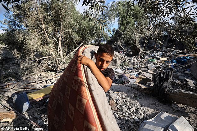 A Palestinian boy salvages a mattress from the rubble of a house in the aftermath of an overnight Israeli strike