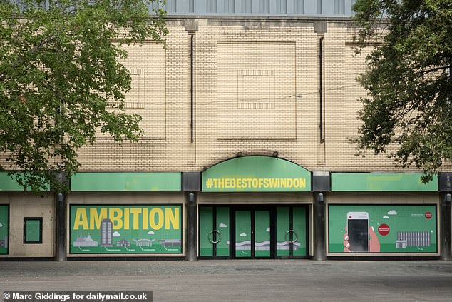 Various signs on the sides of buildings proclaim buzzwords like 'Ambition' and '#TheBestofSwindon' but much of the area is empty