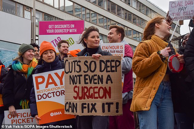 A junior doctor holds a placard which states 'Cuts so deep not even a surgeon can fix it' during a demonstration in London on March 13, 2023