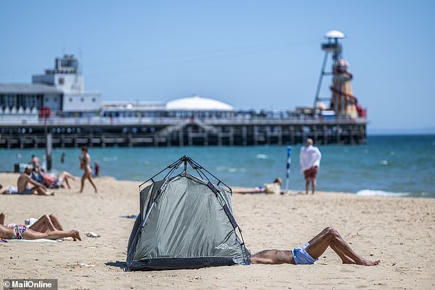 A large green camping tent stands firmly in the sand just yards in front of the duo with a man's legs poking out