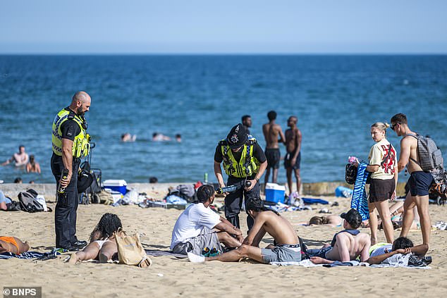 Police officers descend on a group of revelers on Bournemouth beach to seize canisters of nitrous oxide