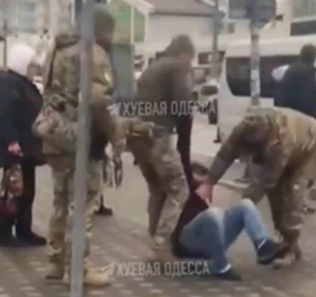 A man is dragged off the street by heavily armed soldiers roaming the streets of Odessa to press gang civilians into the military