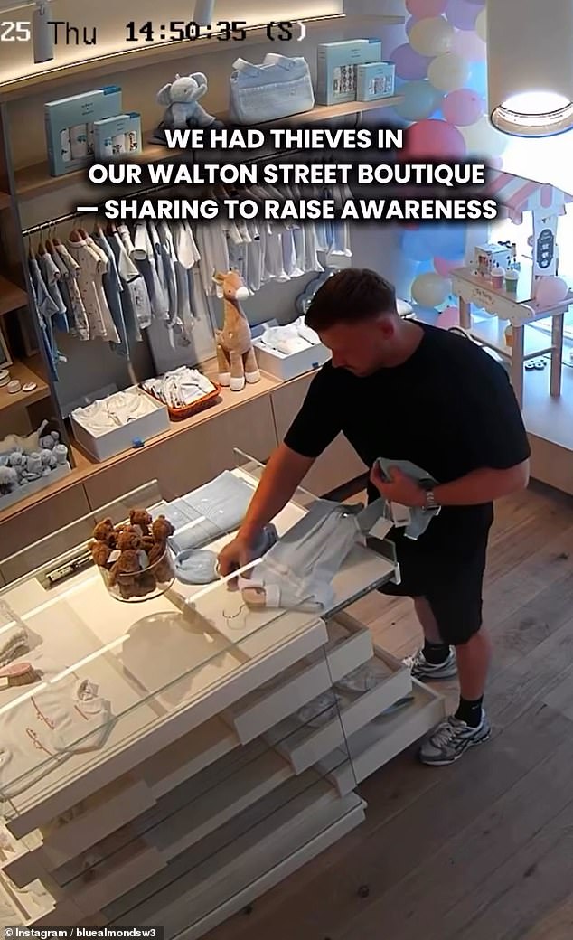 Making sure no one is looking, the thief - who is dressed in all black - shoves a tiny outfit down his clothes, before placing what looks like a baby hat in his pocket and then another item down his shorts