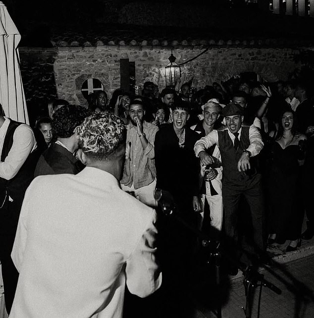 Yamal sings through a microphone in the direction of friends in attendance at the party