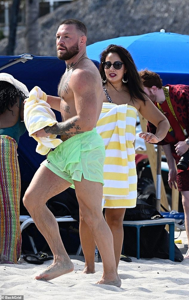 The athlete and the dark haired woman were later spotted standing up and chatting as she wrapped herself in a yellow and white striped towel