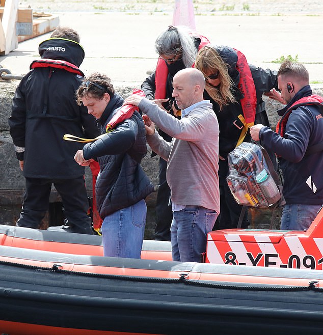 He pulled on a padded black coat to stay warm and a lifejacket for safety, before being whisked away across the sea