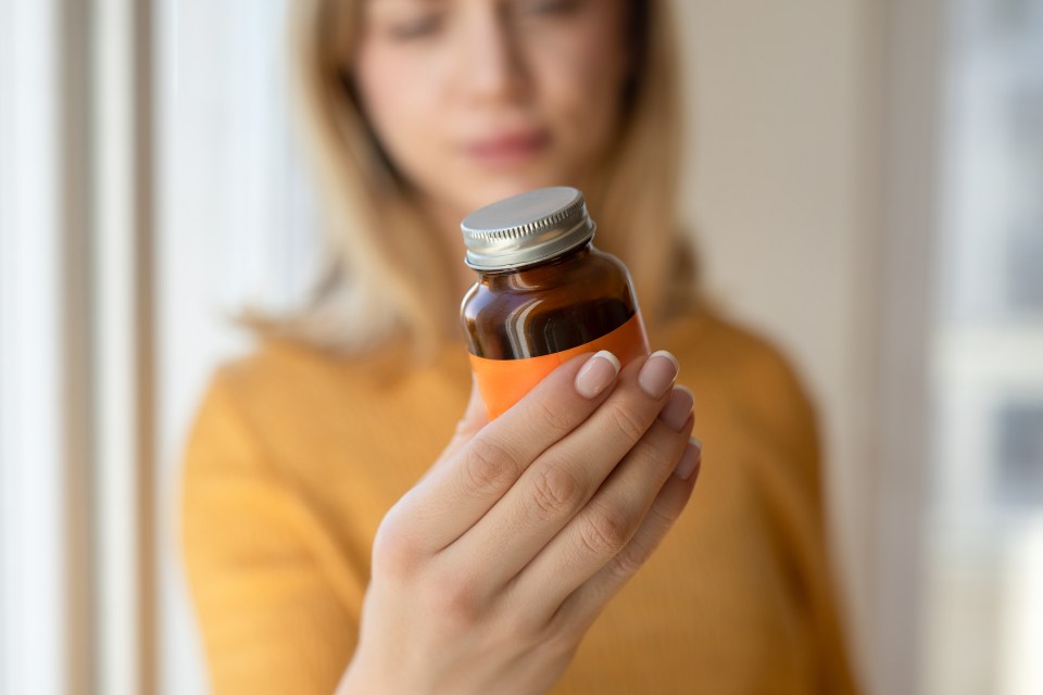 Woman examining a supplement bottle.