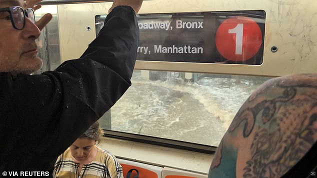 A man looks on from a subway as a station is flooded in New York