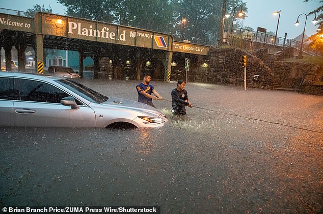 Men try to tow their car out of the rain swell during a flash flood in Plainfield, New Jersey
