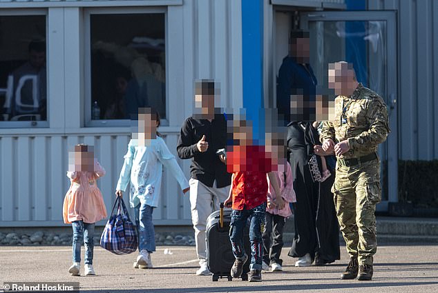 A British soldier speaks to an Afghan family as they leave a hanger