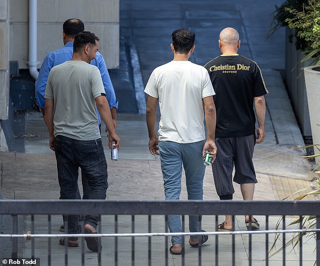 A group of Afghan men moved to Britain as part of the secret scheme exposed by the Daily Mail walk outside their Bracknell hotel