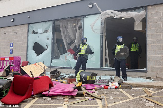 Police officers stand near the broken windows of the hotel in Rotherham on August 4, 2024