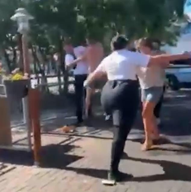 The staff member with a skirt squares up to a lady in a pair of blue shorts and the two have their own mini brawl