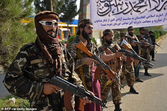 Taliban fighters stand guard near the venue of an open-air rally in a field on the outskirts of Kabul in 2021