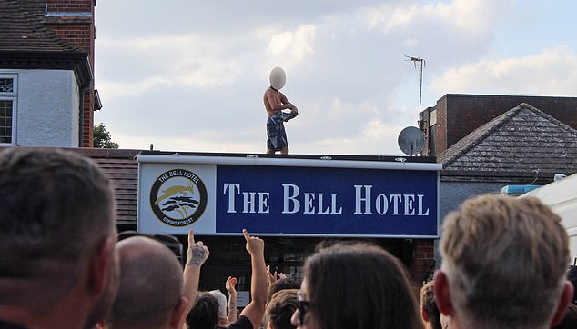 A shirtless man pictured standing on the roof of The Bell Hotel during the protest on Sunday