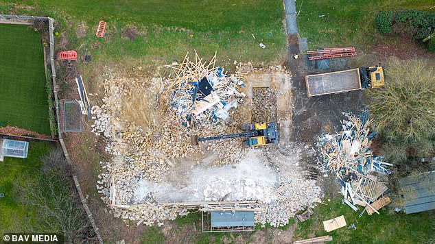 A dumper truck clearing away the rubble from the controversial £200,000 spa complex at the home of Captain Tom Moore's family after it was demolished