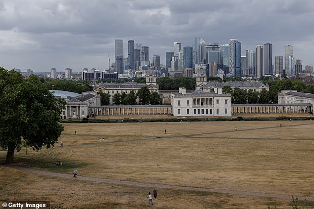 People walk over dried grass at Greenwich Park in South East London yesterday
