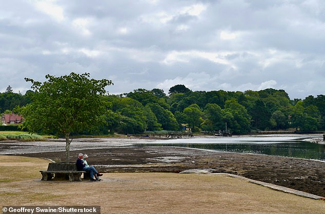 People sit on a bench on dry grass at Beaulieu in the New Forest in Hampshire on Monday