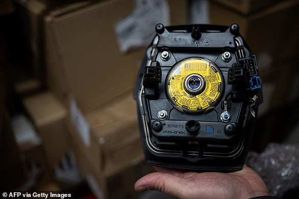 A mechanic holds an airbag module made by the Japanese airbag manufacturer Takata