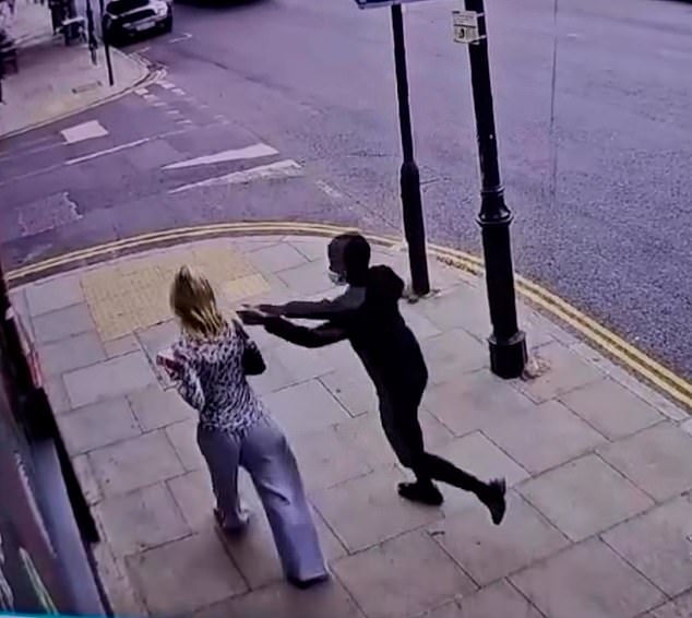 The man dressed in black and wearing a face mask suddenly comes up behind her and snatches the mobile out her hand before sprinting round a corner