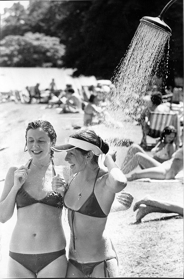 Two young women are seen cooling off with the help of an outdoor shower as temperatures soared during the ten-week heatwave