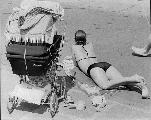 A mother lies in front of her child's pram while enjoy the sun during the hot weather in 1976