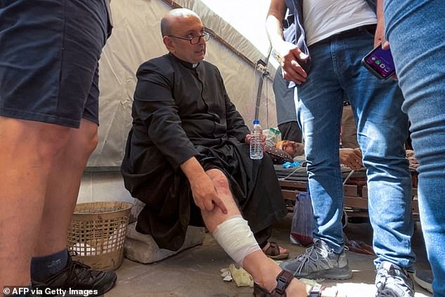 Fr. Gabriel Romanelli receives care after he was injured in an Israeli strike on the church