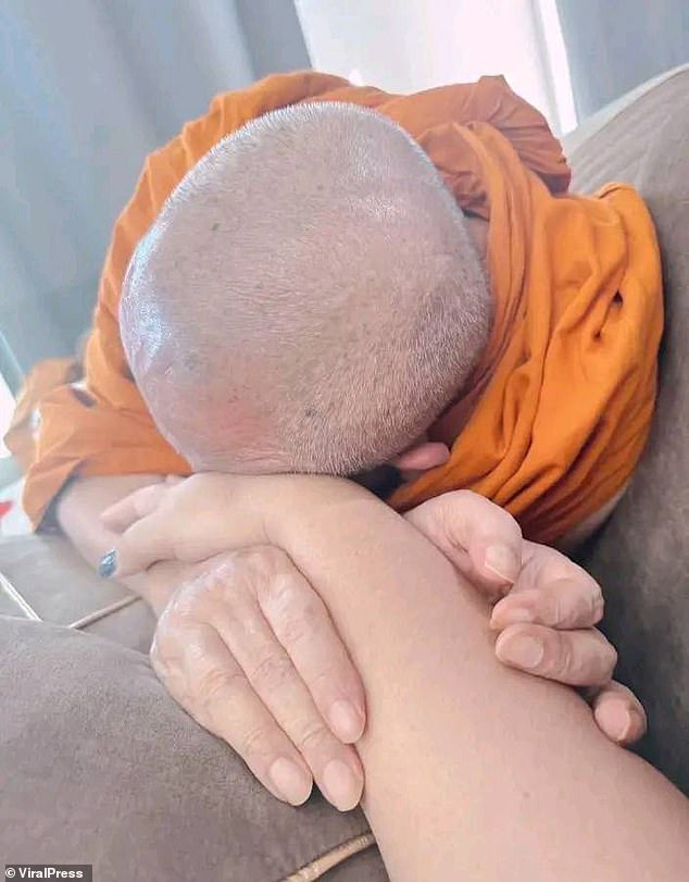 One video shared by police shows a monk reclining on Emsawat on a sofa before she slaps him on the head