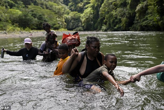 Haitian migrants wade across a river near Bajo Chiquito, Panama, after walking across the Darien Gap from Colombia on their way north to the United States, Saturday, Nov. 9, 2024