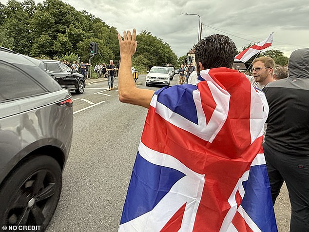 The man waved at passersby with the Union Jack draped over his shoulders