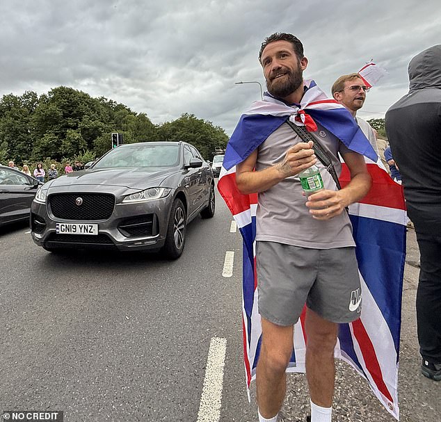 One bearded man wearing shorts draped a union flag over his shoulders as he took selfie pictures outside the embattled hostel