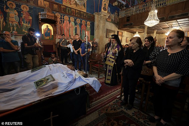 Archbishop Alexios stands in front of the bodies of Palestinian Christians Saad Salama and Foumia Ayyad, who were killed in an Israeli strike on the Holy Family Church