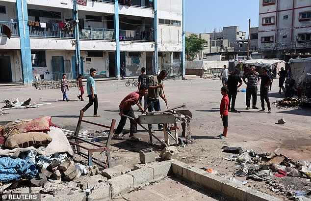 Palestinians inspect the site of an overnight Israeli strike on a school sheltering displaced people, in Bureij refugee camp