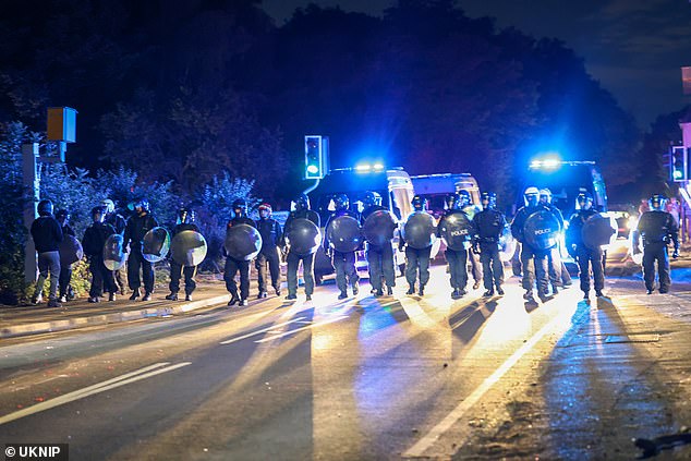 Police armed with riot shields form a barrier across the road following a major public order incident in Epping on Thursday
