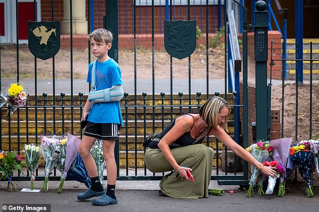 Mother Kim placing her floral tributes with her son Jayden outside the school